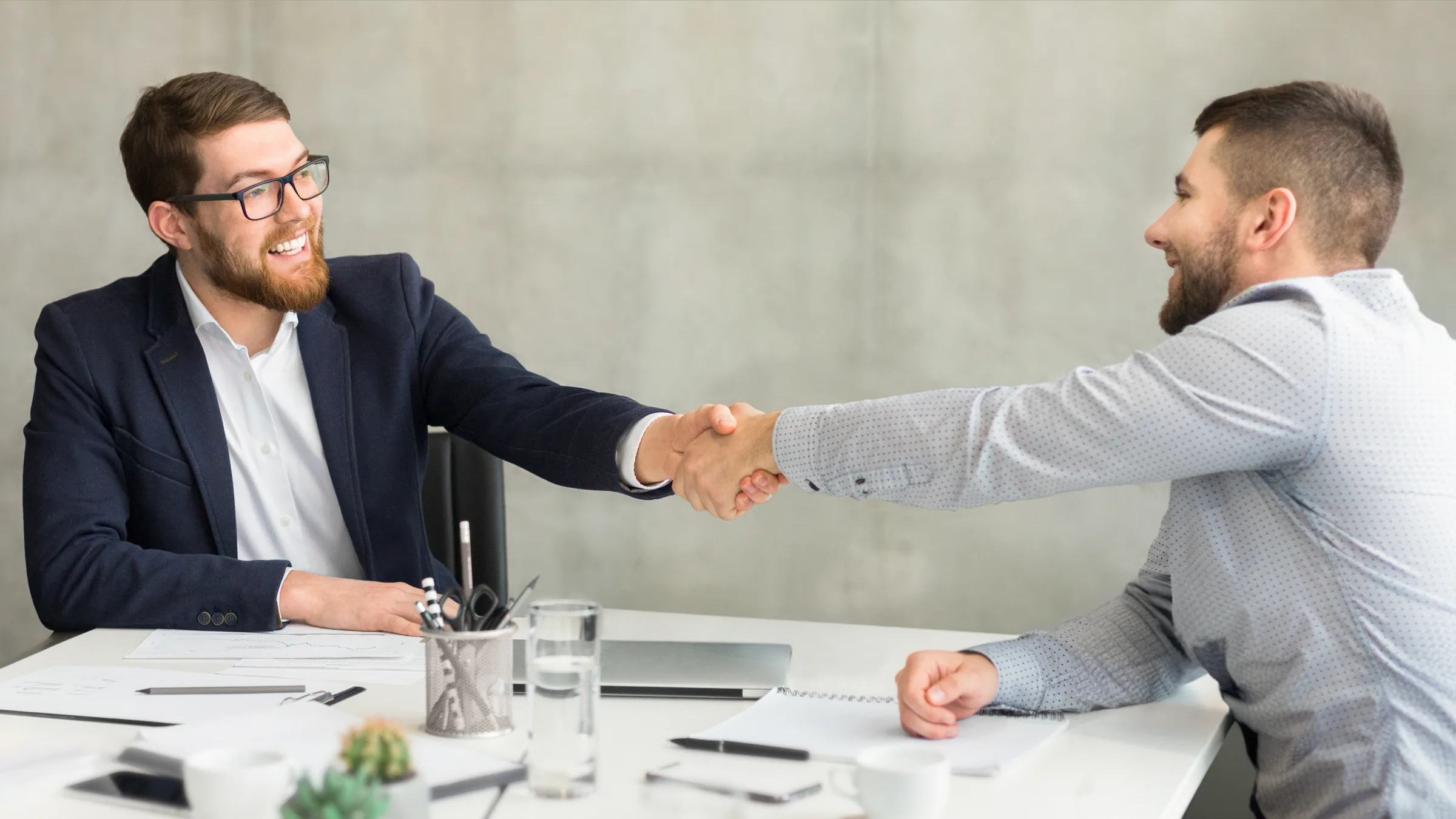 Two professionals shaking hands across a desk